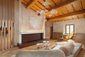 Amplia sala de estar con techo de madera, chimenea, sofá y mesa de comedor con copas de vino.