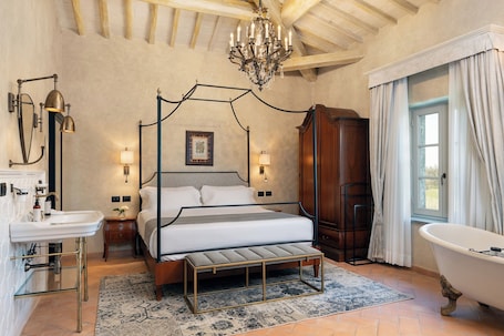 A bedroom with a four-poster bed, a large chandelier, a clawfoot bathtub, and a wooden wardrobe.. Villa Petriolo