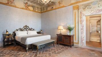 Ein Schlafzimmer mit einem großen Bett, einer Bank, einem Nachttisch, einer Lampe und einem Spiegel.