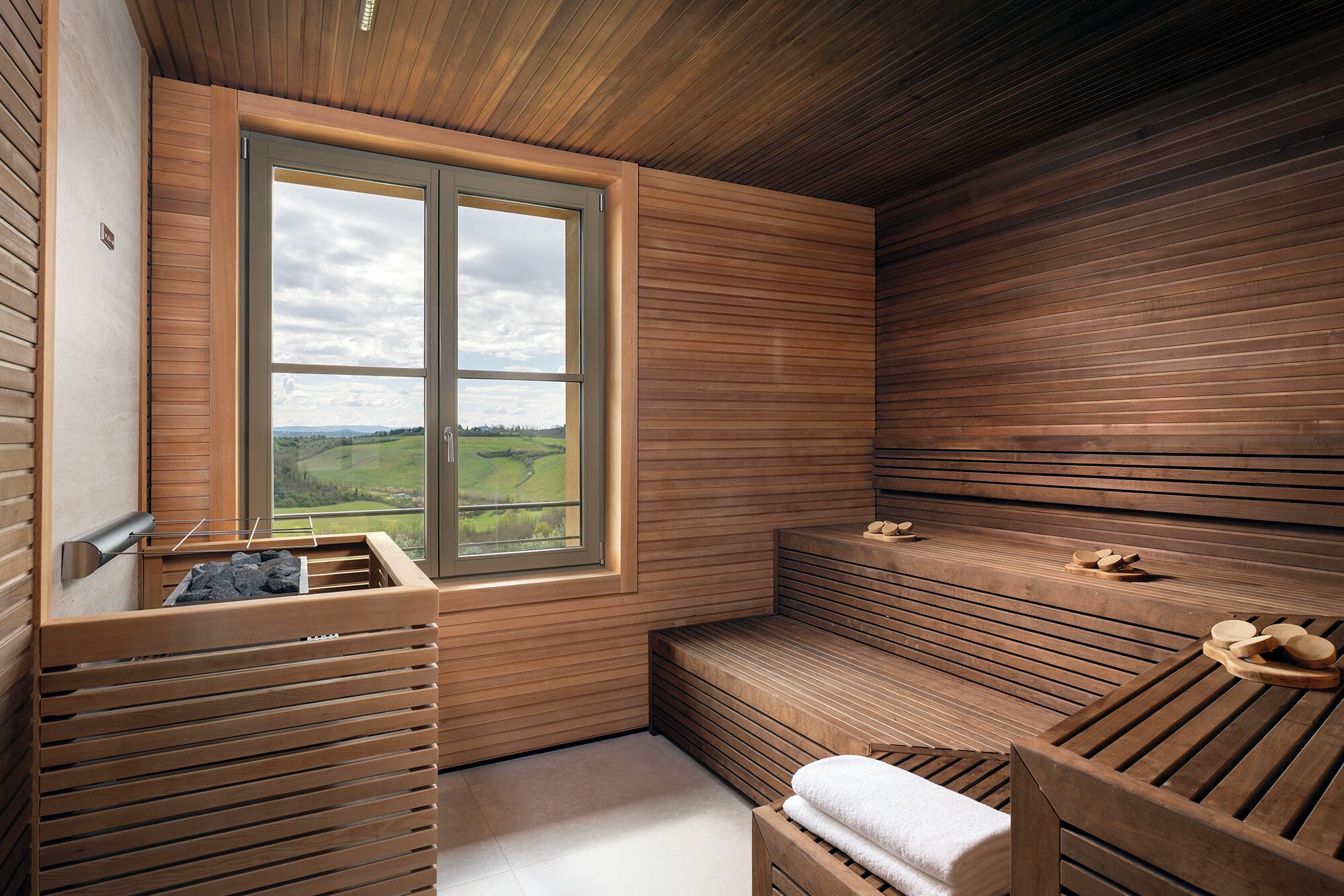 Un sauna avec des bancs en bois, une fenêtre donnant sur la campagne et un porte-serviettes.