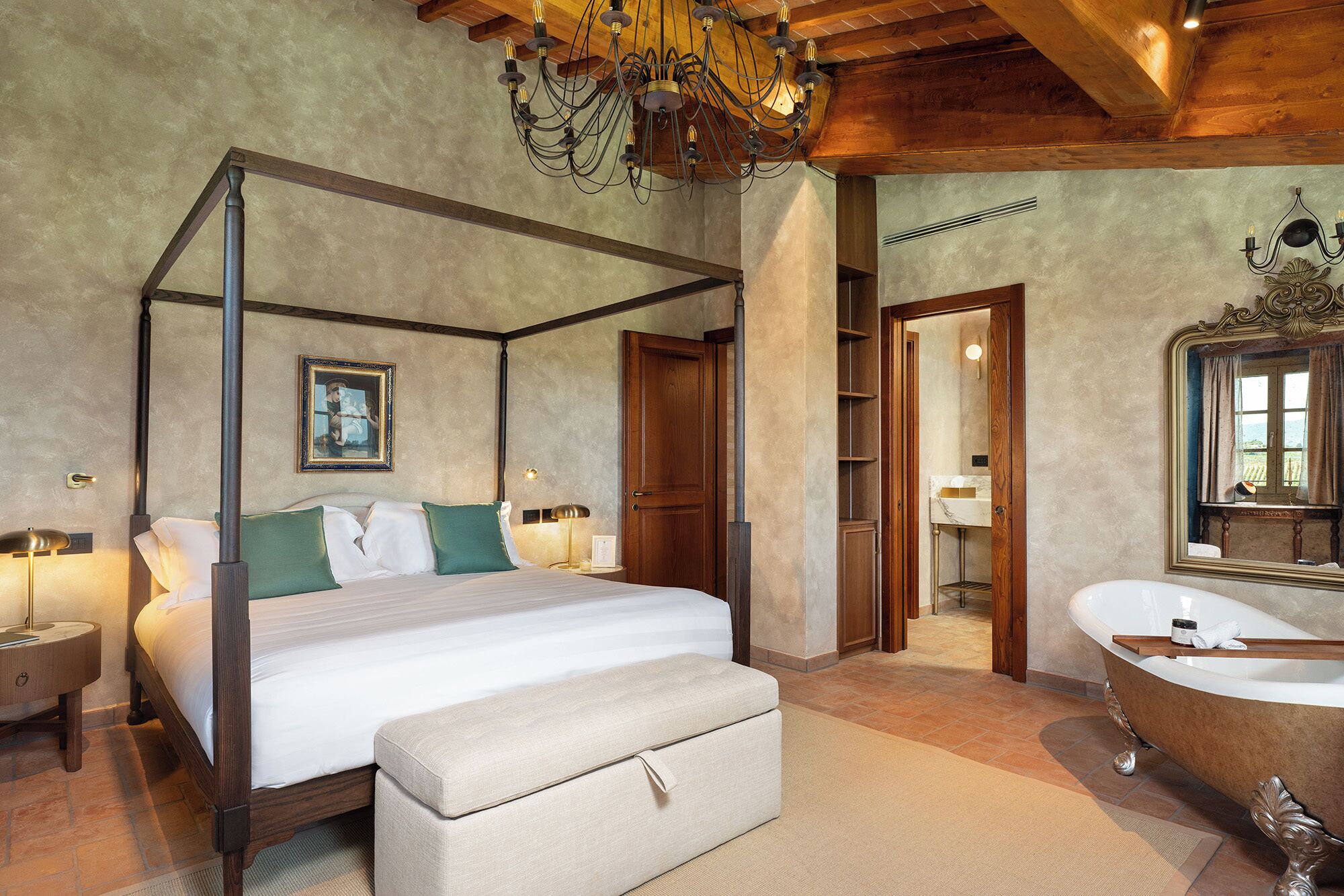 A four-poster bed with a bench, a bathtub, and a chandelier.