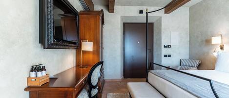Une chambre à coucher comprenant un lit, un bureau, une chaise, un miroir, un lustre et une porte.