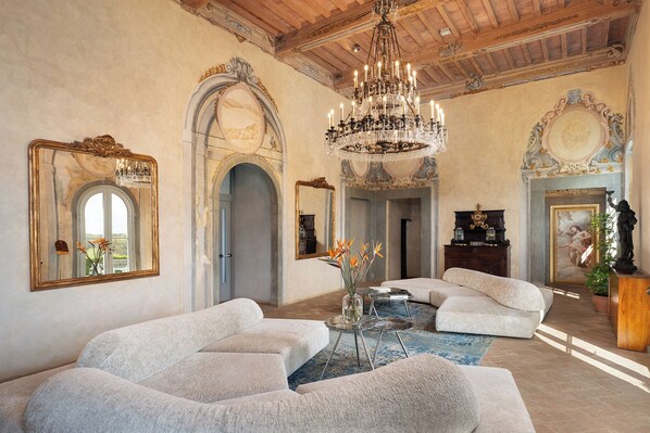 A spacious room with a chandelier, large mirrors, and a grand staircase.