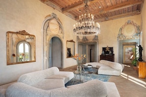A spacious room with a chandelier, large mirrors, and a grand staircase.