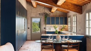 Una cocina con zona de comedor, vigas de madera en el techo y vistas al exterior.