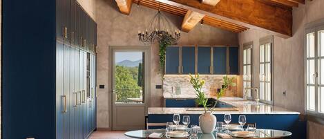 A kitchen with a dining area, wooden ceiling beams, and a view of the outdoors.