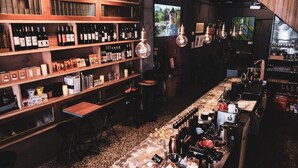 A bar area with shelves of wine bottles, a coffee machine, and a television screen. - Island House (Kaohsiung)