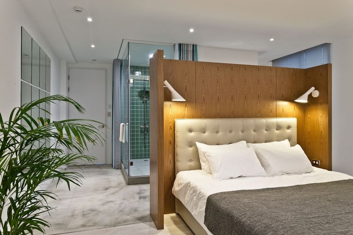 Um quarto moderno com cabeceira estofada, uma cama grande e uma luminária de cabeceira.