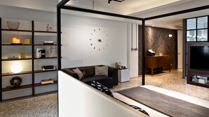 A modern living room with a sofa, a coffee table, a bookshelf, a wall clock, and a TV. - Island House (Kaohsiung)