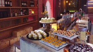 A bar area with shelves of bottles, a dessert display, and a bar counter with glasses and bottles. - Island House (Kaohsiung)