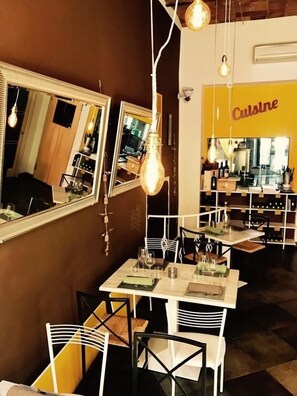 A restaurant interior with mirrored walls, hanging light fixtures, and a 'Cuisine' sign. - Il Giardino Dei Limoni (Suvereto)