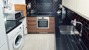Una cocina compacta con lavadora, microondas y horno empotrado.
