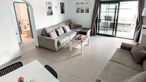 Una sala moderna con sofá, mesa de centro y comedor con mesa y sillas.