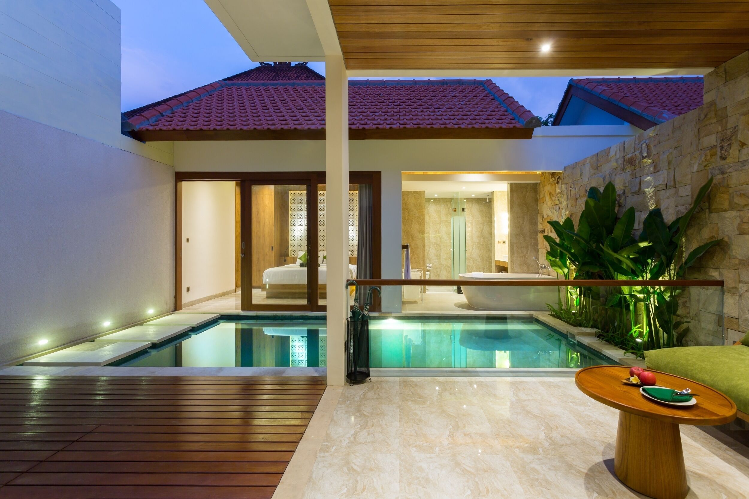 A modern house with a swimming pool, a wooden deck, and a stone wall.