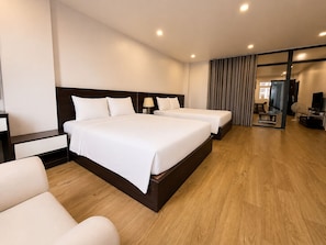 A hotel room with two beds, a sofa, a TV, and a dining area. - The Nova Hotel & Apartment (Hai Phong)