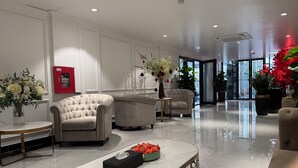 A modern lobby with plush seating, a reception desk, and a fire extinguisher on the wall.