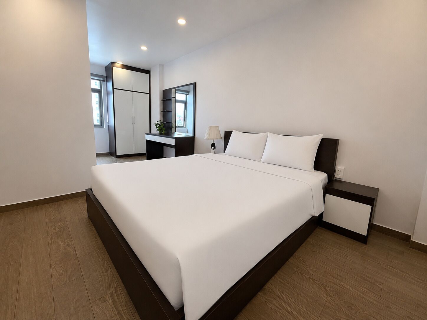 A modern hotel room with a large bed, a desk, and a mirror.