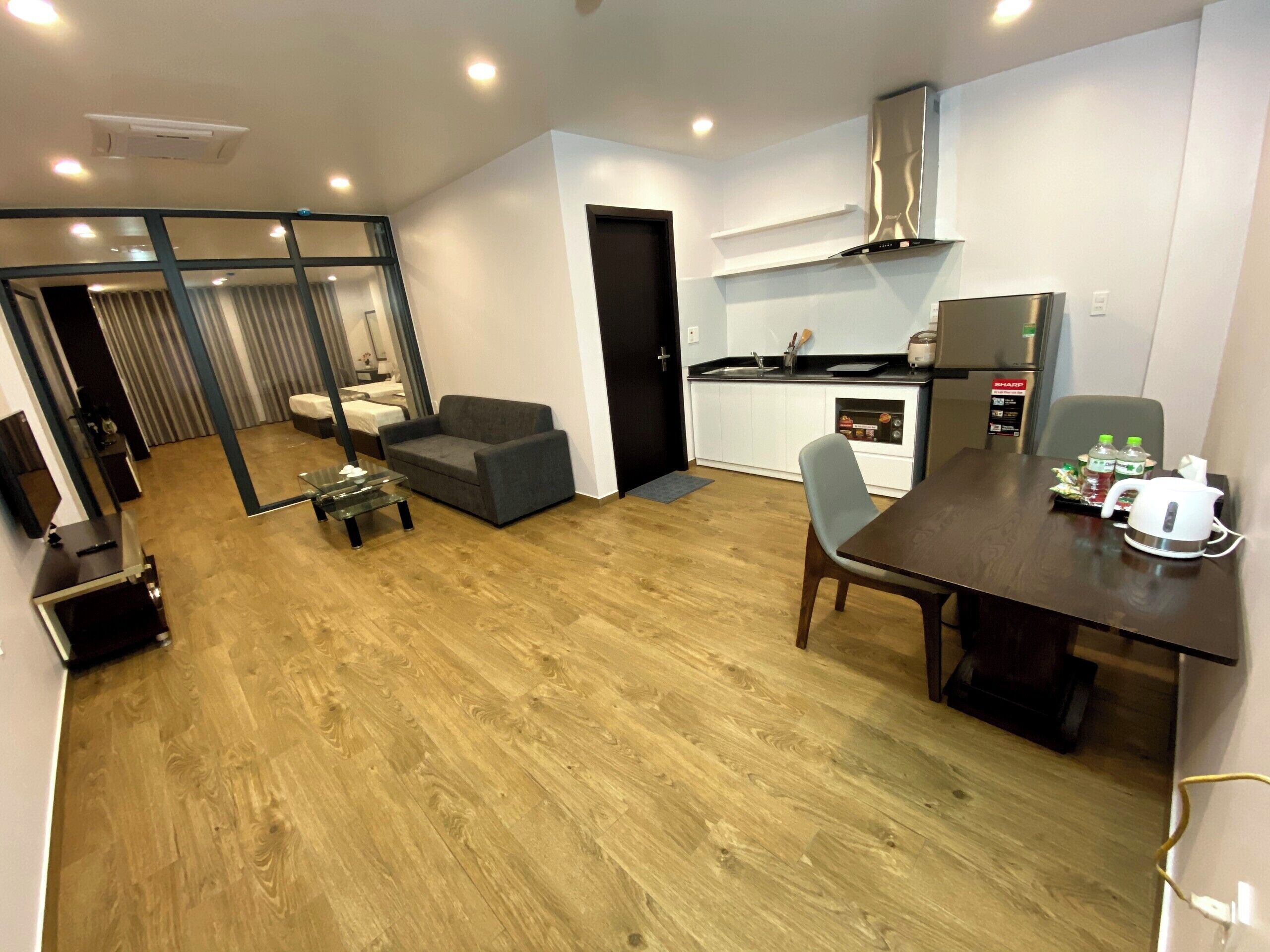 A modern hotel room with a dining area, kitchenette, and a separate living space.