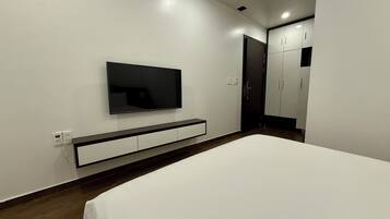 A modern bedroom with a bed, a TV mounted on the wall, and a wardrobe.