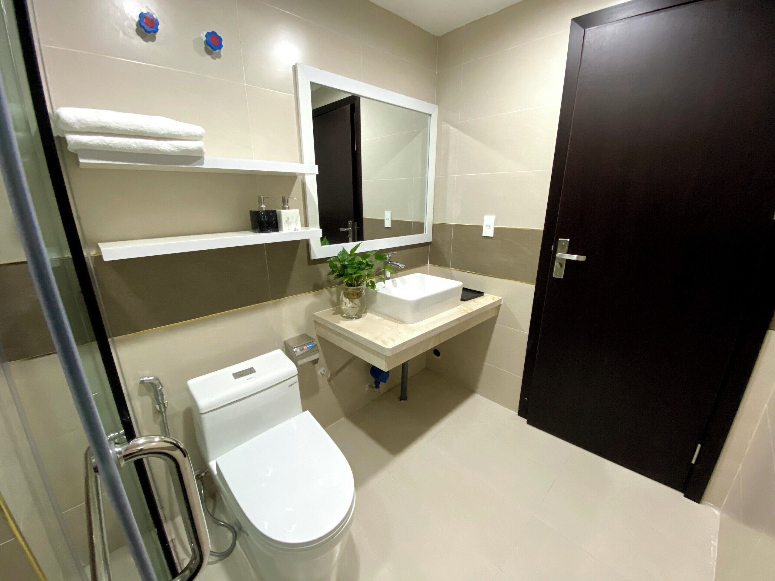 Une salle de bain moderne avec des toilettes, un lavabo, un miroir et une porte sombre.