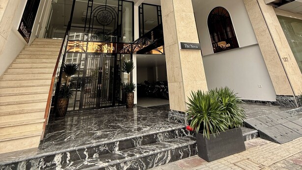 A hotel entrance with a marble staircase, a black awning, and a sign reading 'The Nova.'