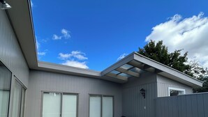 A modern patio with wicker furniture, a barbecue grill, and a covered area.