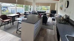 A modern kitchen with a central island, wooden beams on the ceiling, and large windows offering a view of the outside.