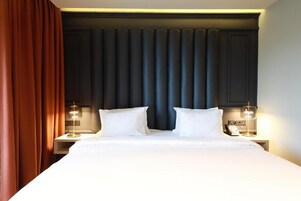 Ein Hotelzimmer mit einem großen Bett, zwei Nachttischen mit Lampen und einem dunklen Kopfteil.