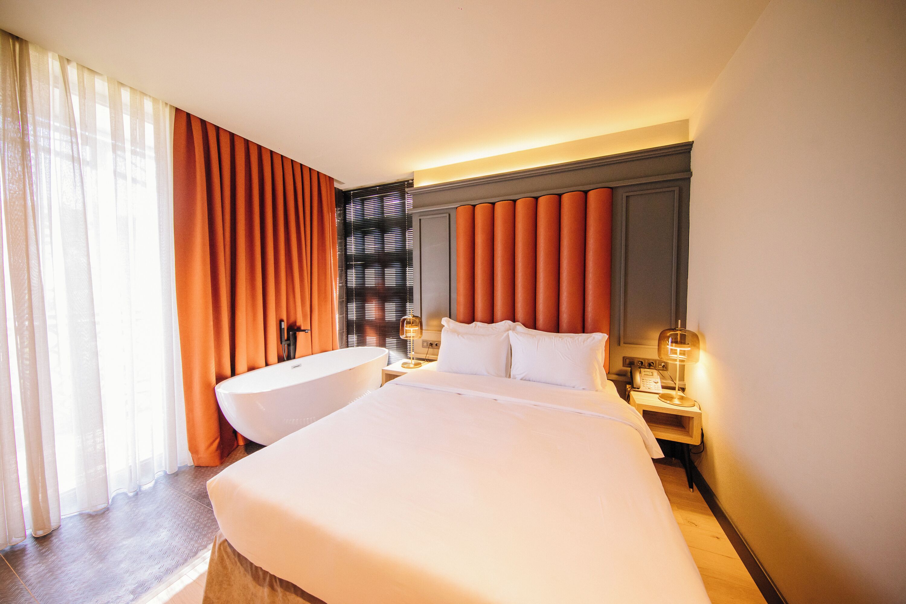 A hotel room with a large bed, a bathtub, and a vanity with a mirror.
