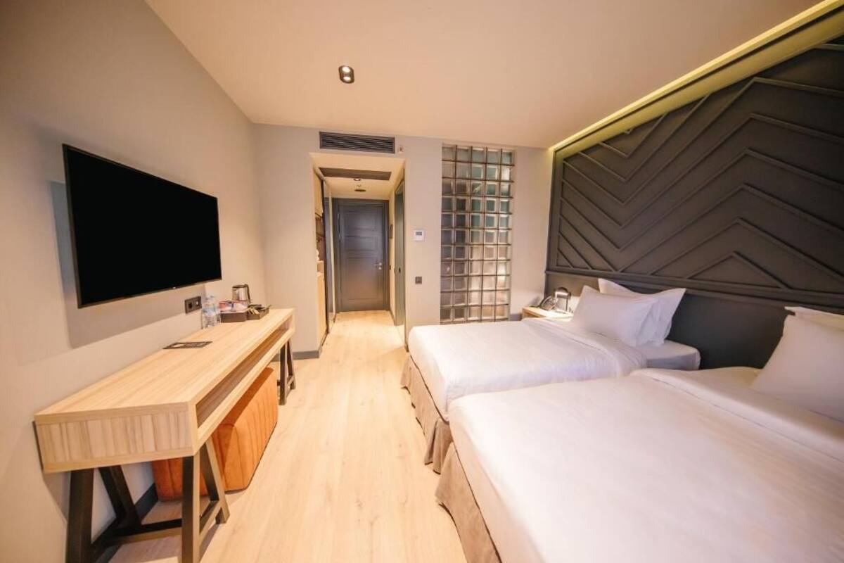 A hotel room with two beds, a TV, a desk, and a walk-in closet.
