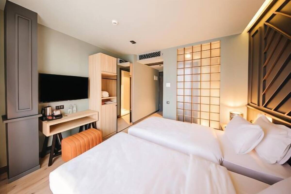 A hotel room with a bed, a TV, a desk, and a wardrobe.