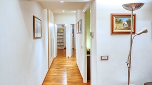 Un couloir doté d’un plancher en bois, de murs blancs et d’une porte donnant sur une pièce.