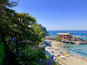 Uma área costeira com praia, barcos e um edifício com telhado vermelho.