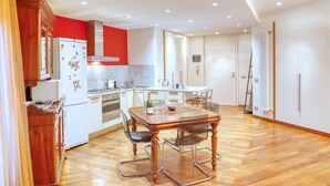 Une cuisine moderne avec un coin repas, un plancher en bois et des meubles de rangement blancs.