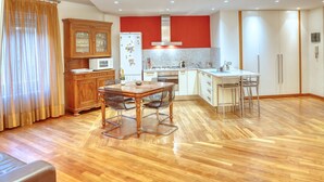 Une cuisine moderne avec un coin repas, des meubles en bois et un mur d’accent rouge.