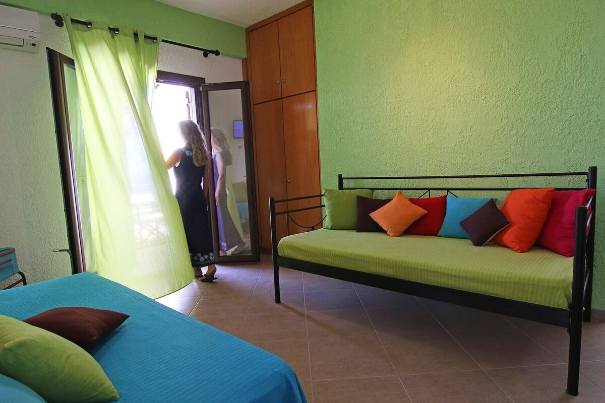 A room with a bed, a sofa, a wardrobe, and a window with curtains.