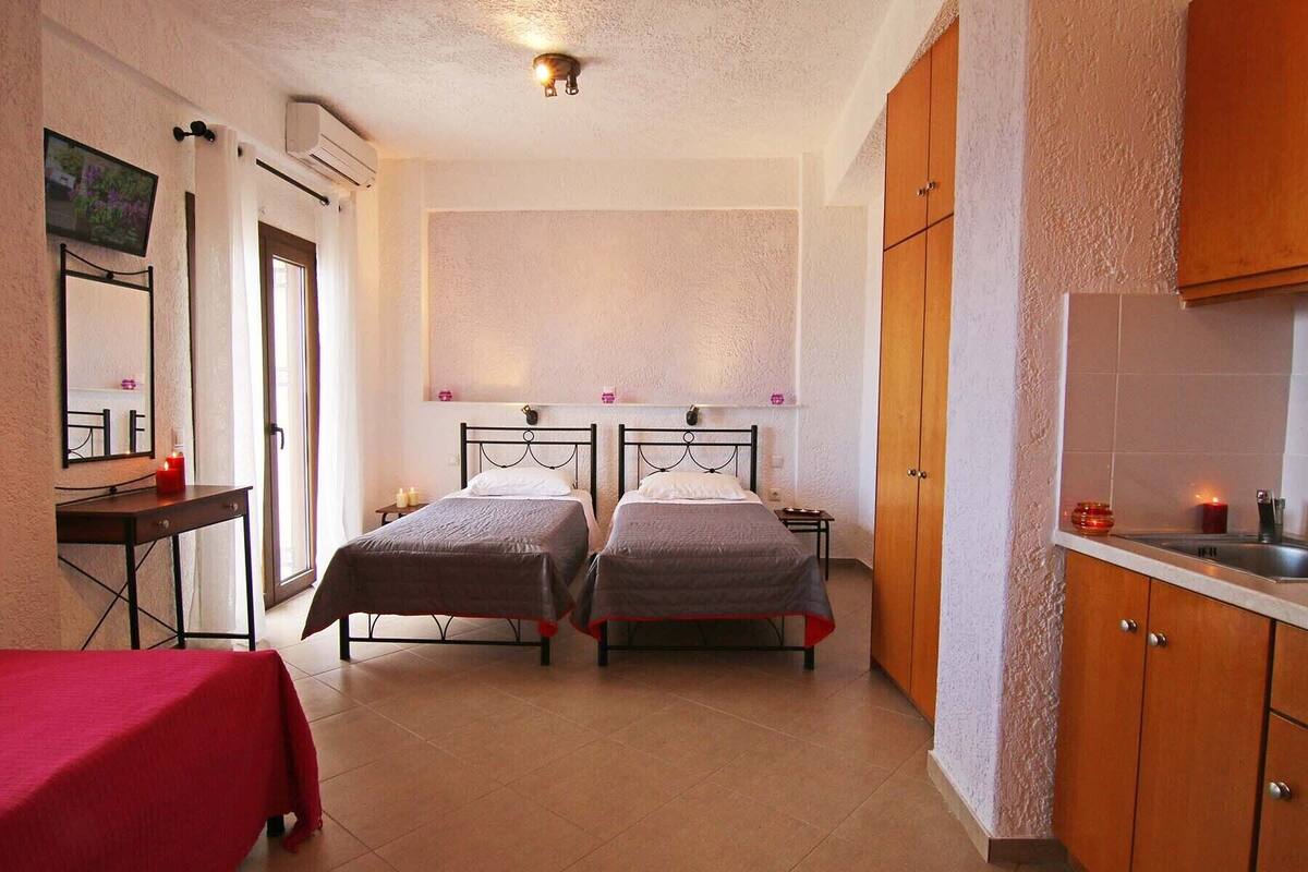 A room with two beds, a small table, a mirror, and a cabinet.