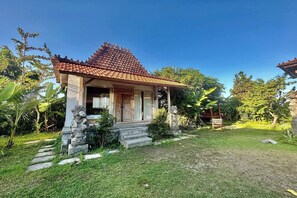 A traditional house with a tiled roof, a porch, and a stone statue. - Bali Eco Living Yoga Healing Meditation and Retreat Center (Denpasar)