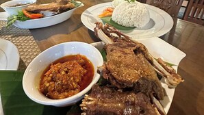 A dining table with a variety of dishes including grilled meat, rice, and a bowl of sauce. - Balian Yoga Shala (Denpasar)