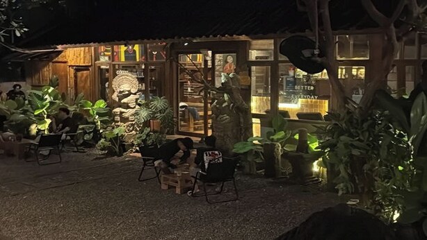 A building with a glass facade, outdoor seating, and potted plants. - Balian Yoga Shala (Denpasar)