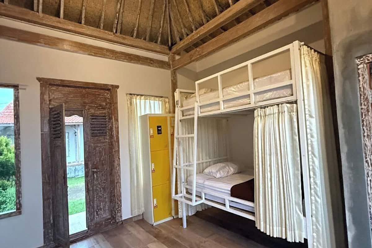 A room with a wooden ceiling, bunk beds, a yellow door, and a window.