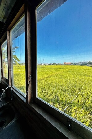 A room with a large window overlooking a green field. - Bali Eco Living Yoga Healing Meditation and Retreat Center (Denpasar)