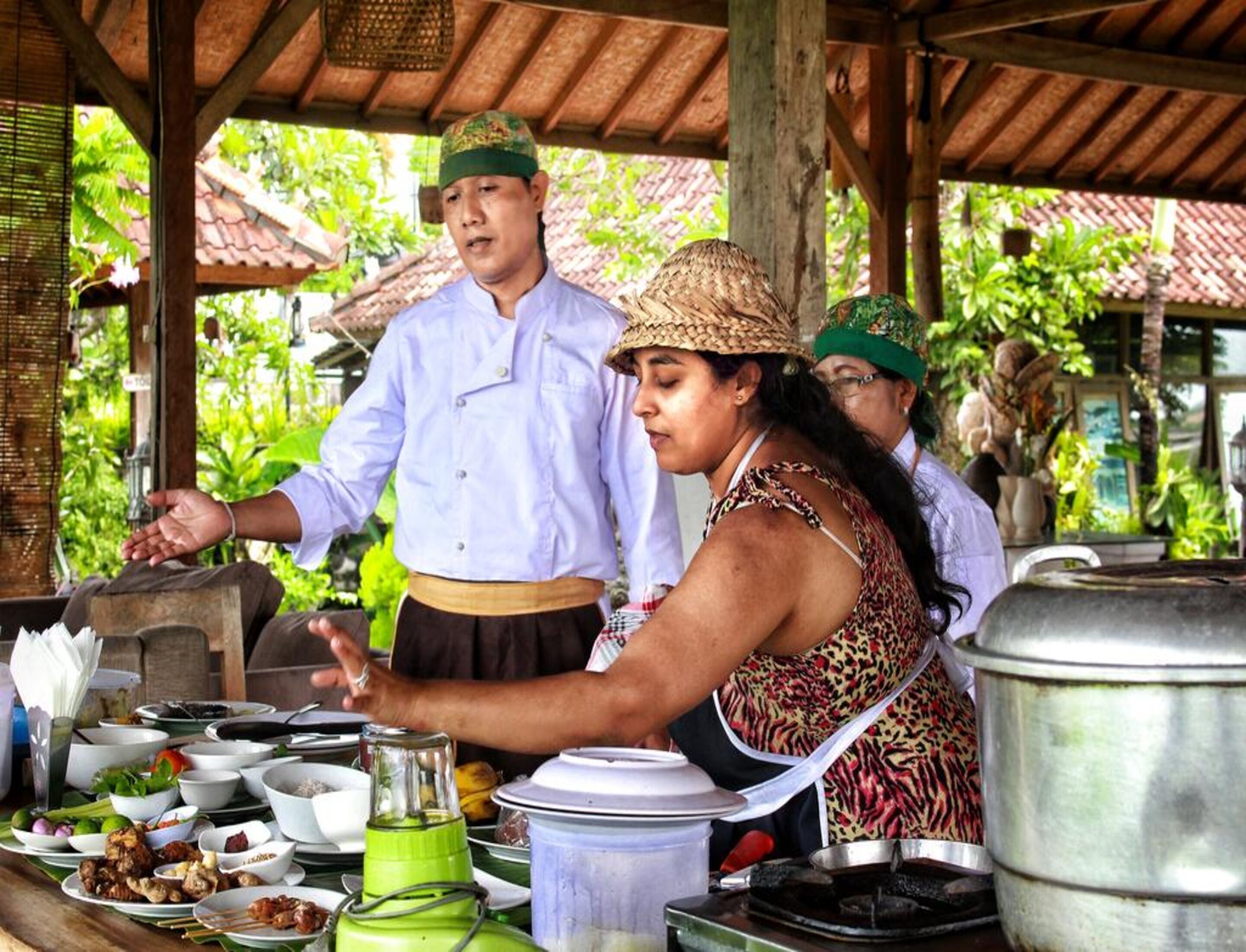 A food stall with various dishes and cooking equipment, set under a wooden shelter with a tiled roof.