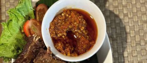 A plate of grilled meat with a side of sauce and vegetables.