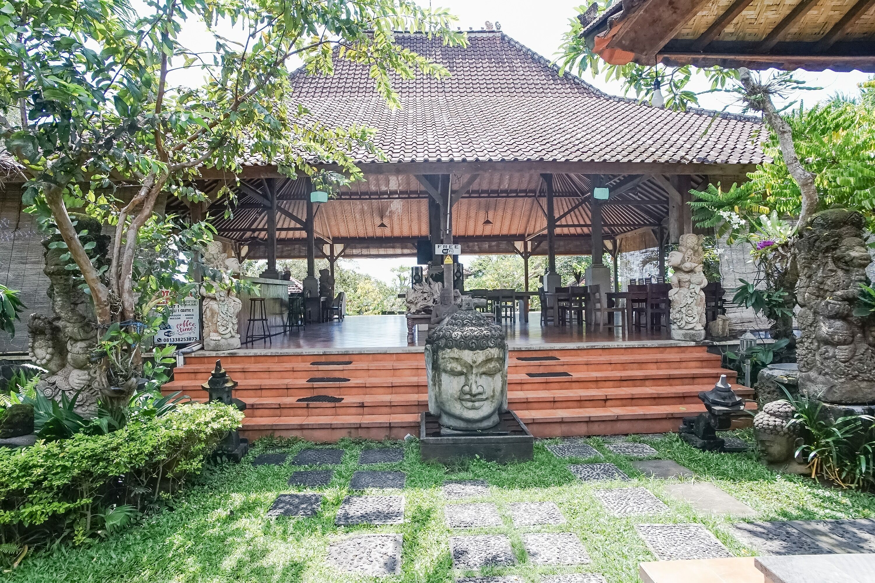 Ein traditioneller Pavillon mit Ziegeldach, Steinfiguren und einem steinbelagten Weg zum Eingang.