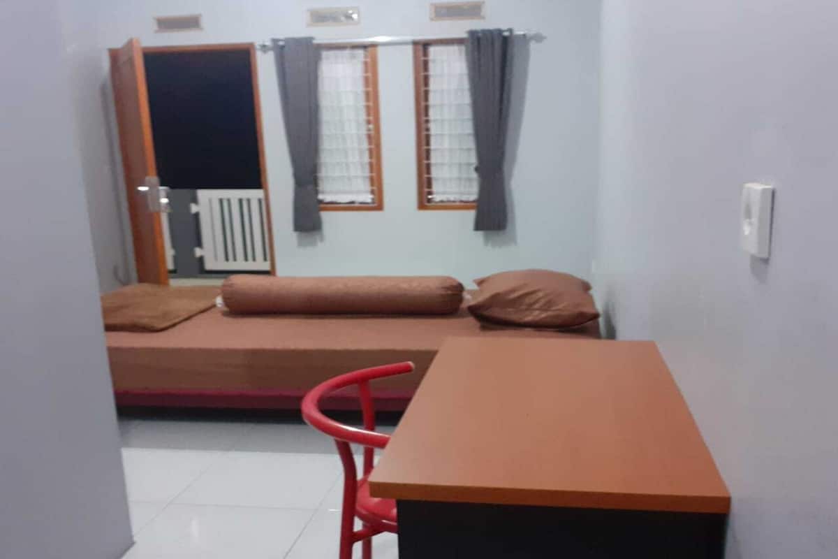 Ein kleines Zimmer mit einem Bett, einem Schreibtisch und einem Stuhl.