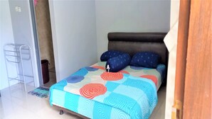 A bedroom with a bed, a bedside table, and a chair. - Nabila Syar'i Guesthouse (Ngamprah)