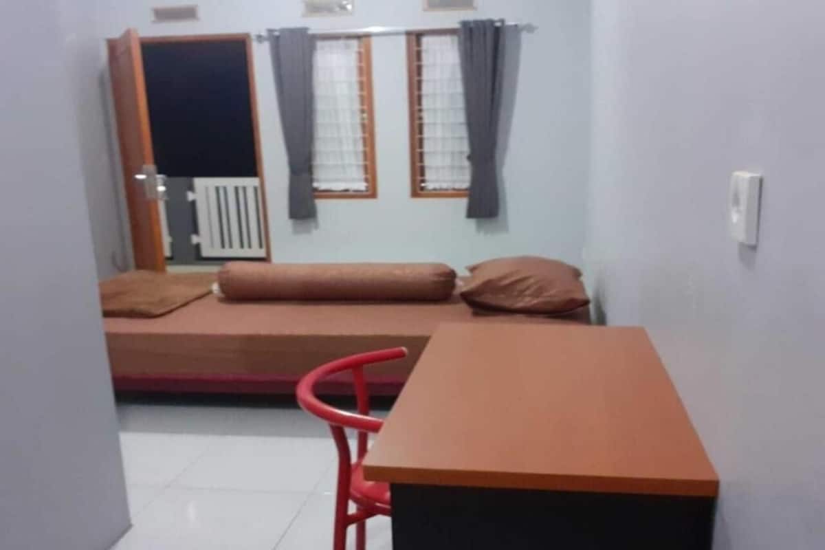Ein kleines Zimmer mit einem Bett, einem Tisch und einem Stuhl.