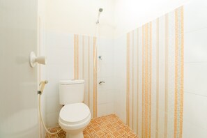 Un baño pequeño con inodoro, ducha y paredes a rayas.