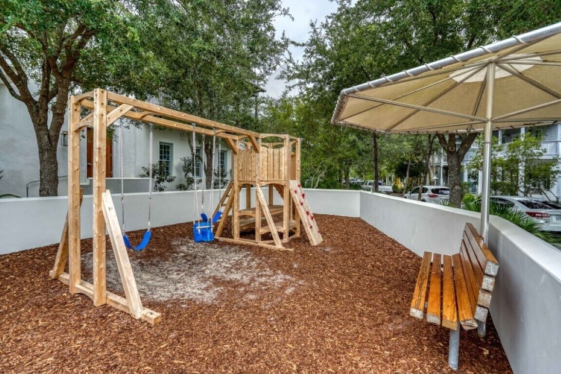Un conjunto de columpios de madera en un área de juegos techada, con un banco y una marquesina.